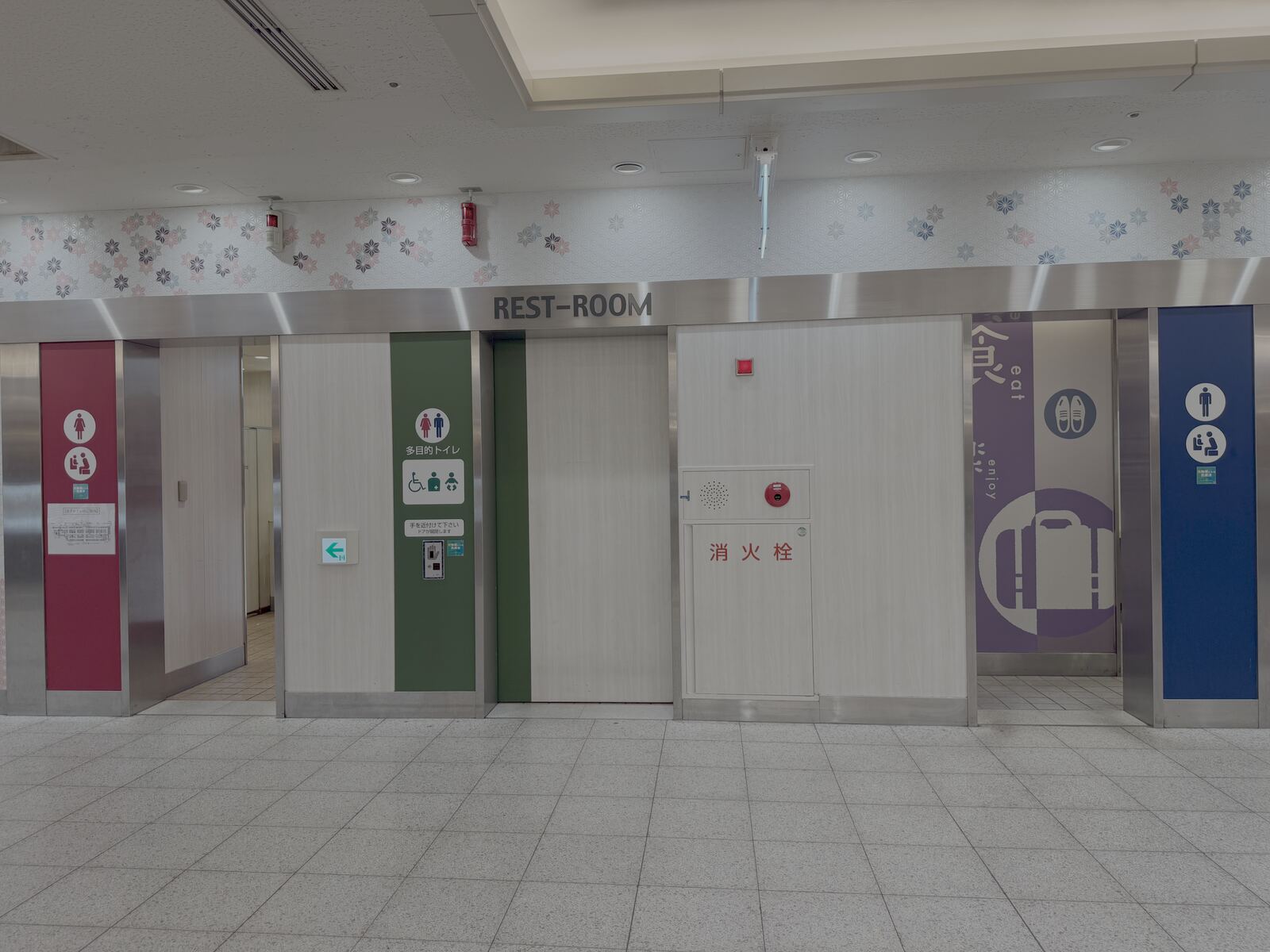 Rest-room sign and multi-purpose toilet entrance in the ESCA underground mall, with wheelchair, baby-seat and ostomate pictograms.