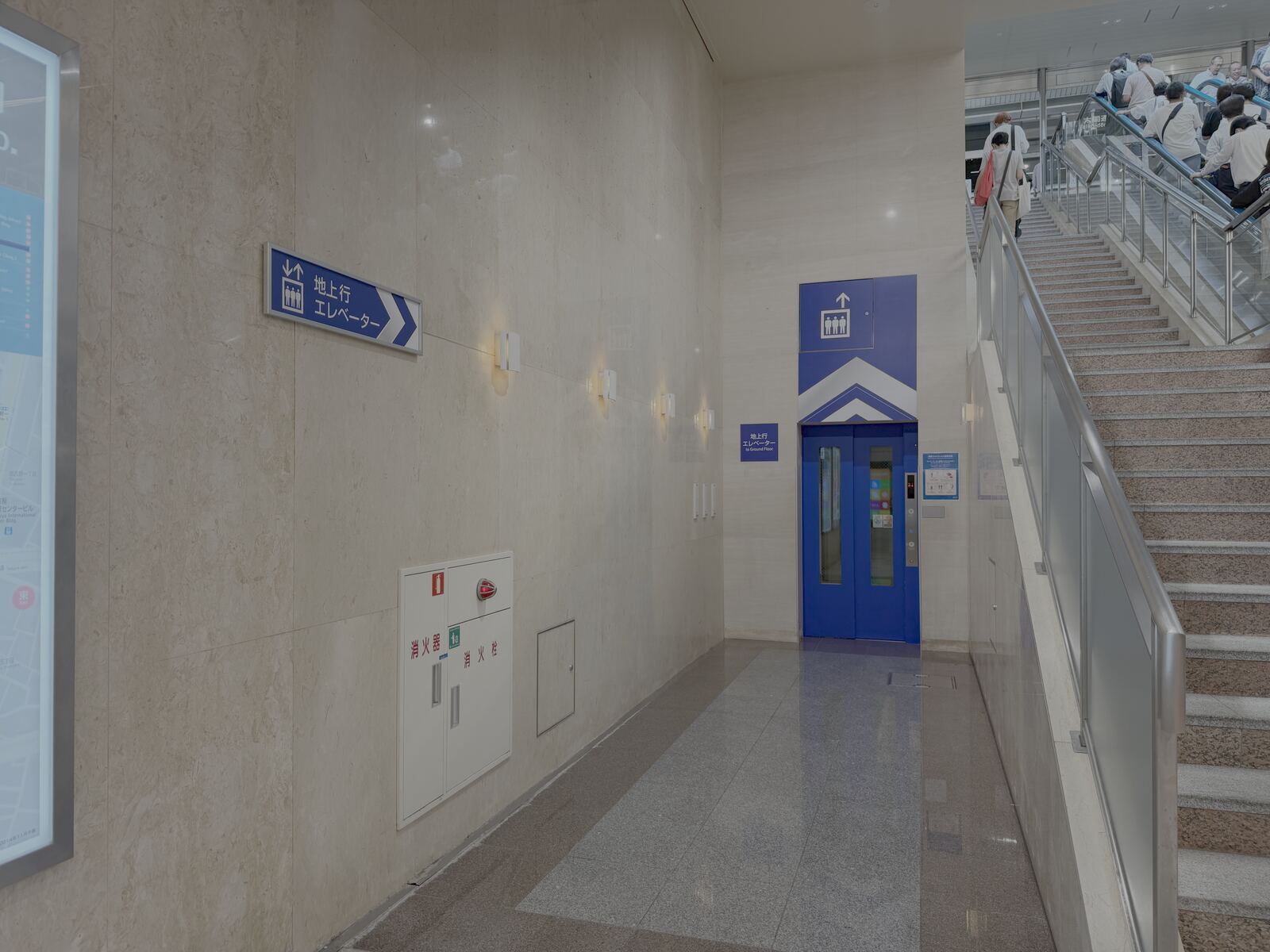 Blue elevator doors in the ESCA underground mall passageway, with a sign for the elevator to ground floor.