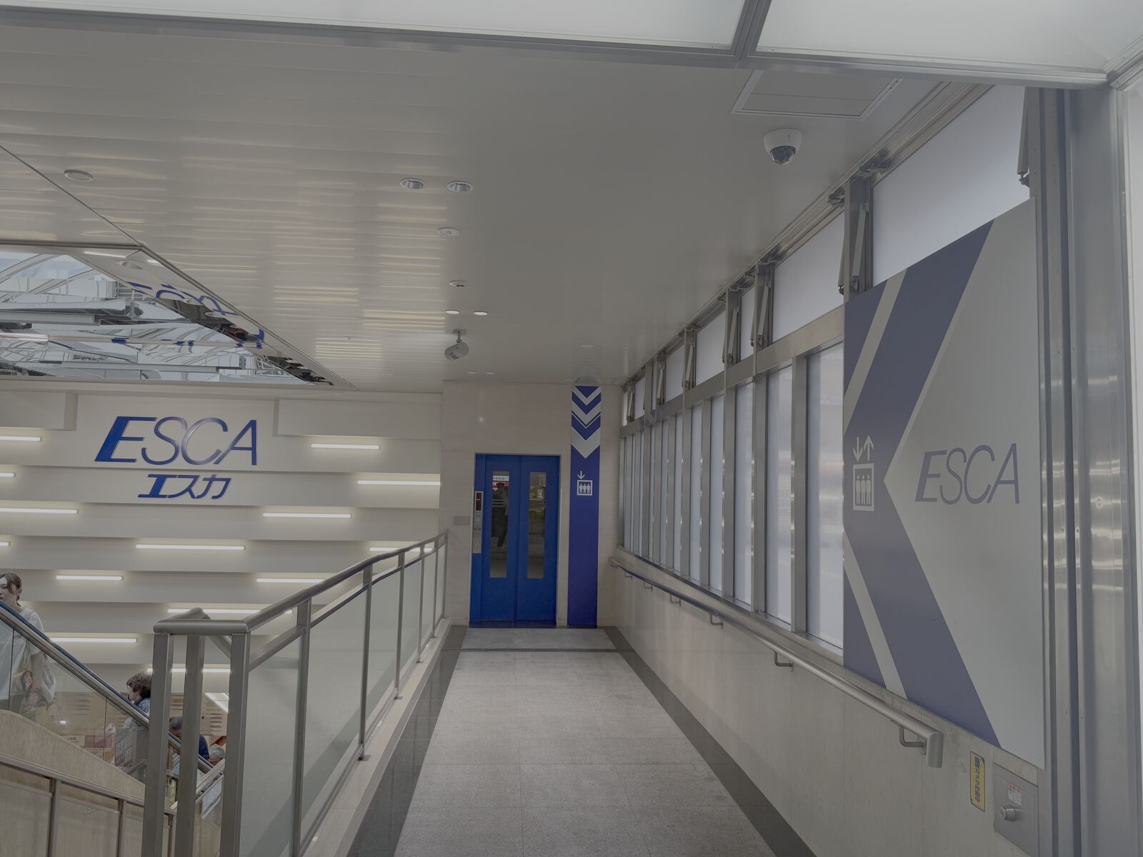 Blue elevator doors in the ESCA underground mall passageway, a second angle.
