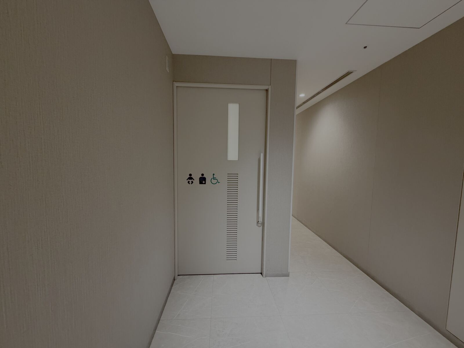 Accessible toilet door with wheelchair, baby-seat and ostomate pictograms in the Kitachika underground passage.
